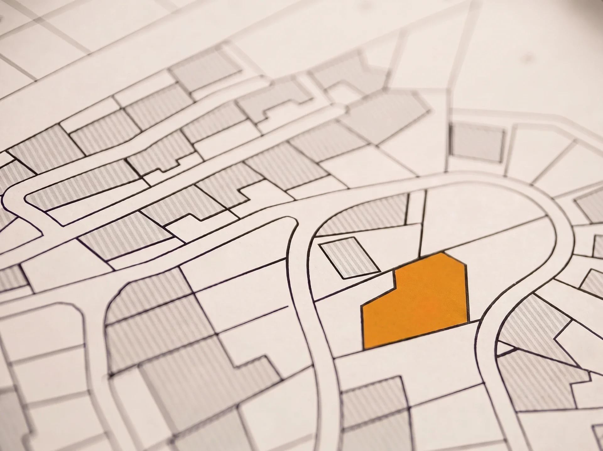 Stadsplankarta med en orange markerad fastighet bland grå kvarter.